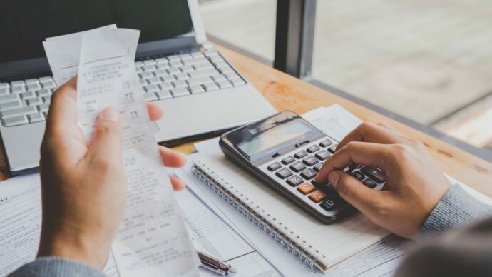 young-man-using-calculator-calculate-bills-home-office